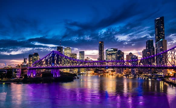 Brisbane city skyline at twilight with Story Bridge illuminated in purple